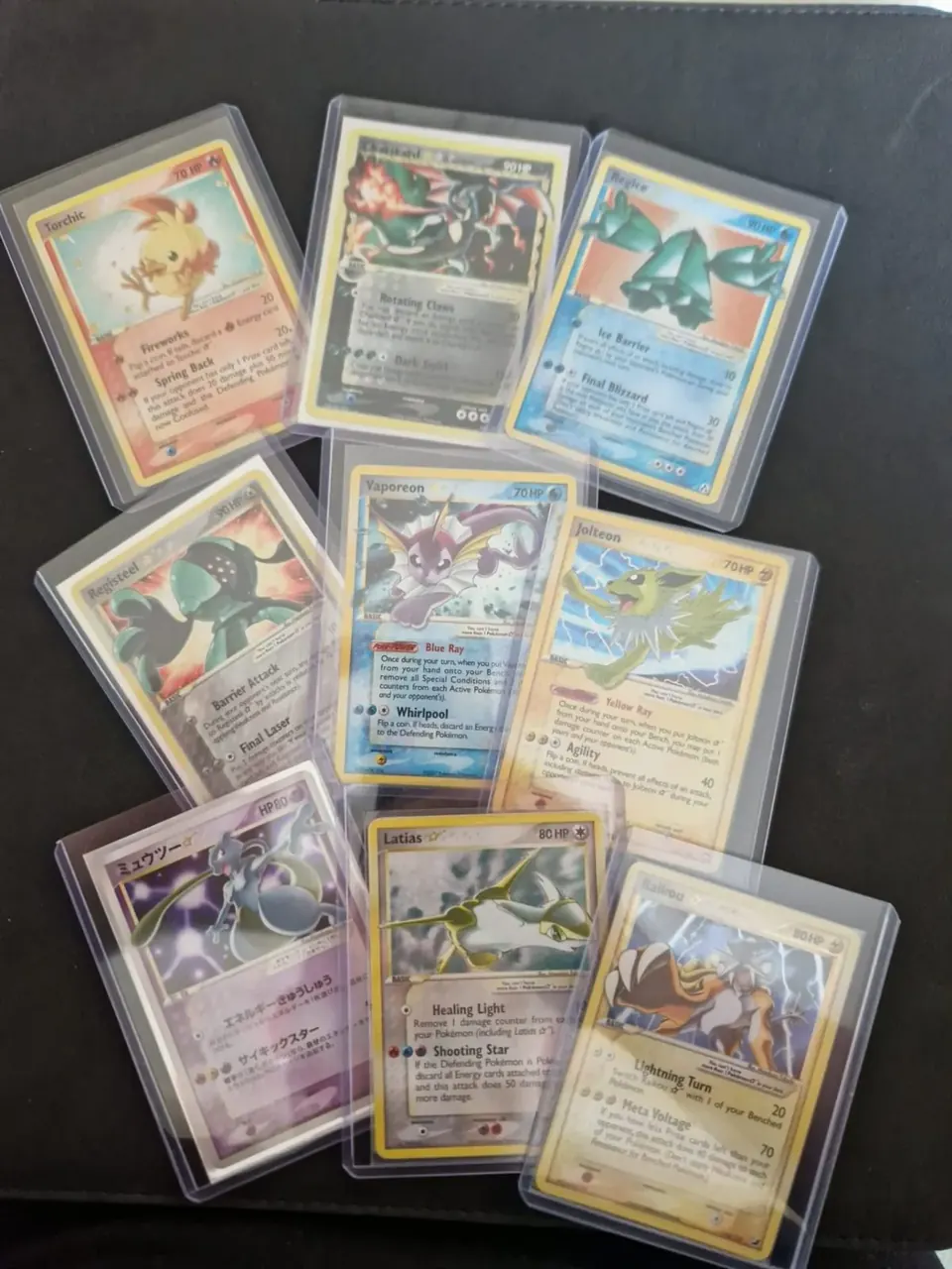 Gold Star Pokémon karte u zaštitnim toploaderima na stolu: Charizard, Vaporeon, Jolteon, Latias i drugi